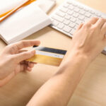 Woman,With,Credit,Card,Using,Computer,At,Table