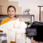 Young,Asian,Woman,Live,Online,Clothing,Store,While,Showing,Clothing